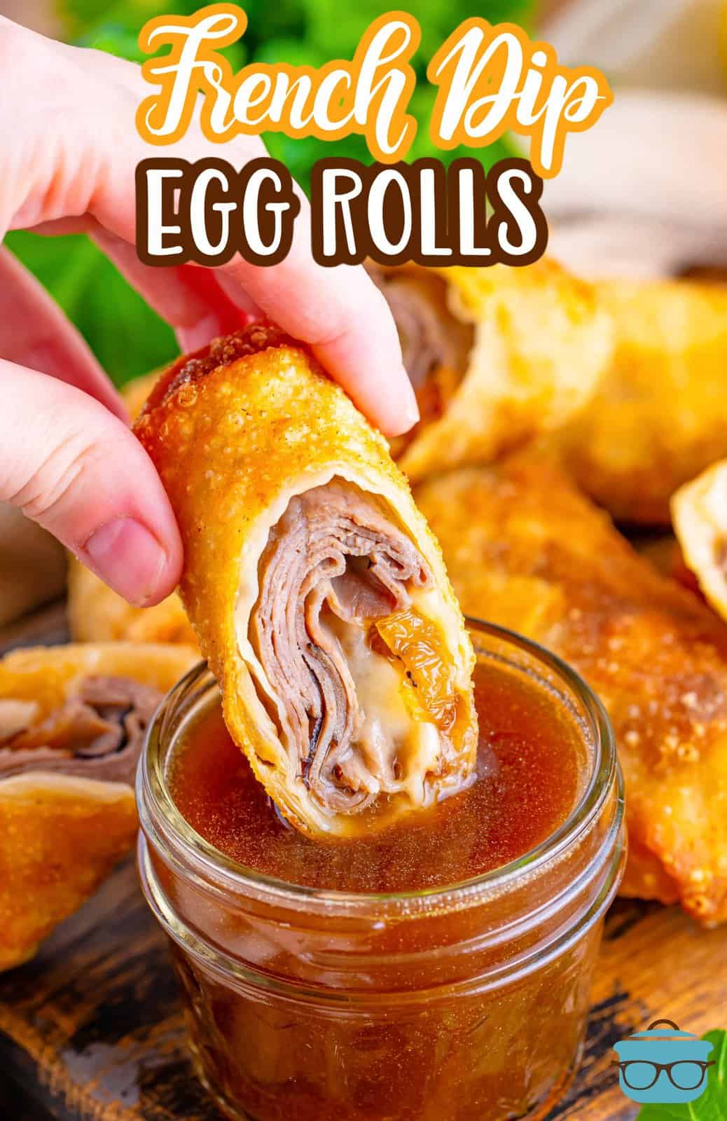A hand holding a French Dip egg roll and dipping it in sauce.