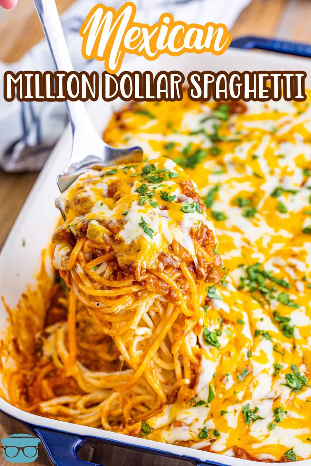 Serving utensil holding a serving of Mexican million dollar spaghetti over a baking dish.