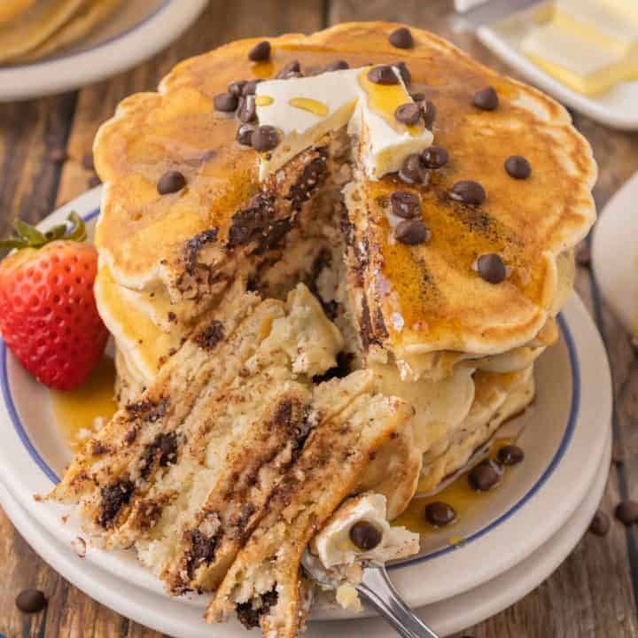 Stack of chocolate chip pancakes with a slice taken out ready to eat.
