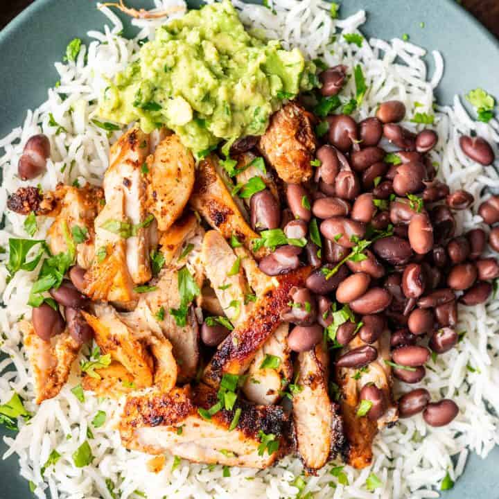 Chipotle chicken with beans, and rice on a plate.