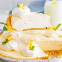 A slice of Lemonade Pie being held over the rest of the pie.