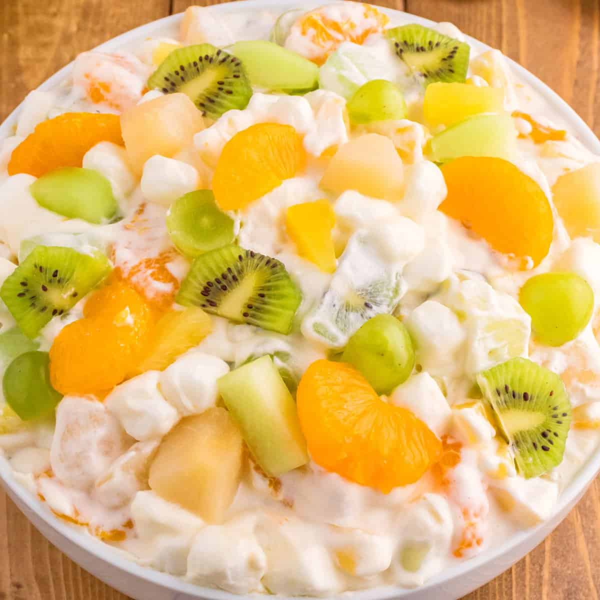 A bowl of ambrosia salad with green and orange or gold ingredients.