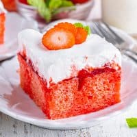 Close up looking at a single serving of strawberry poke cake with a strawberry on top.