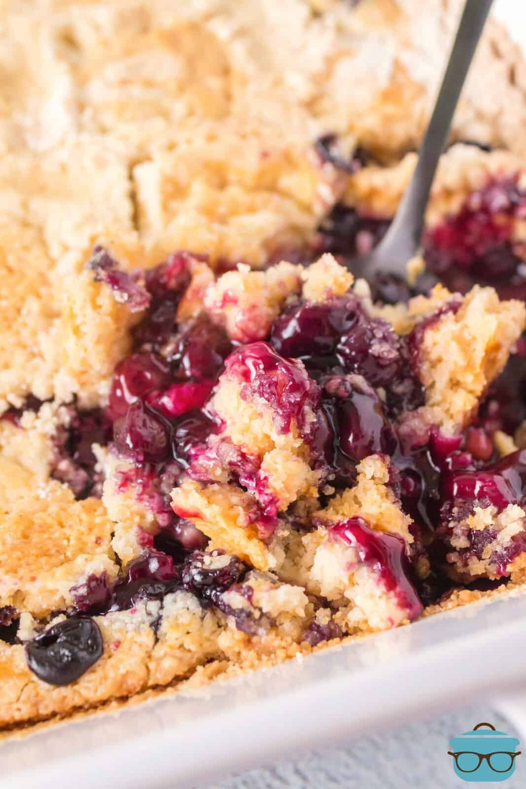A serving utensil getting a serving of Blueberry Dump Cake out of the dish.