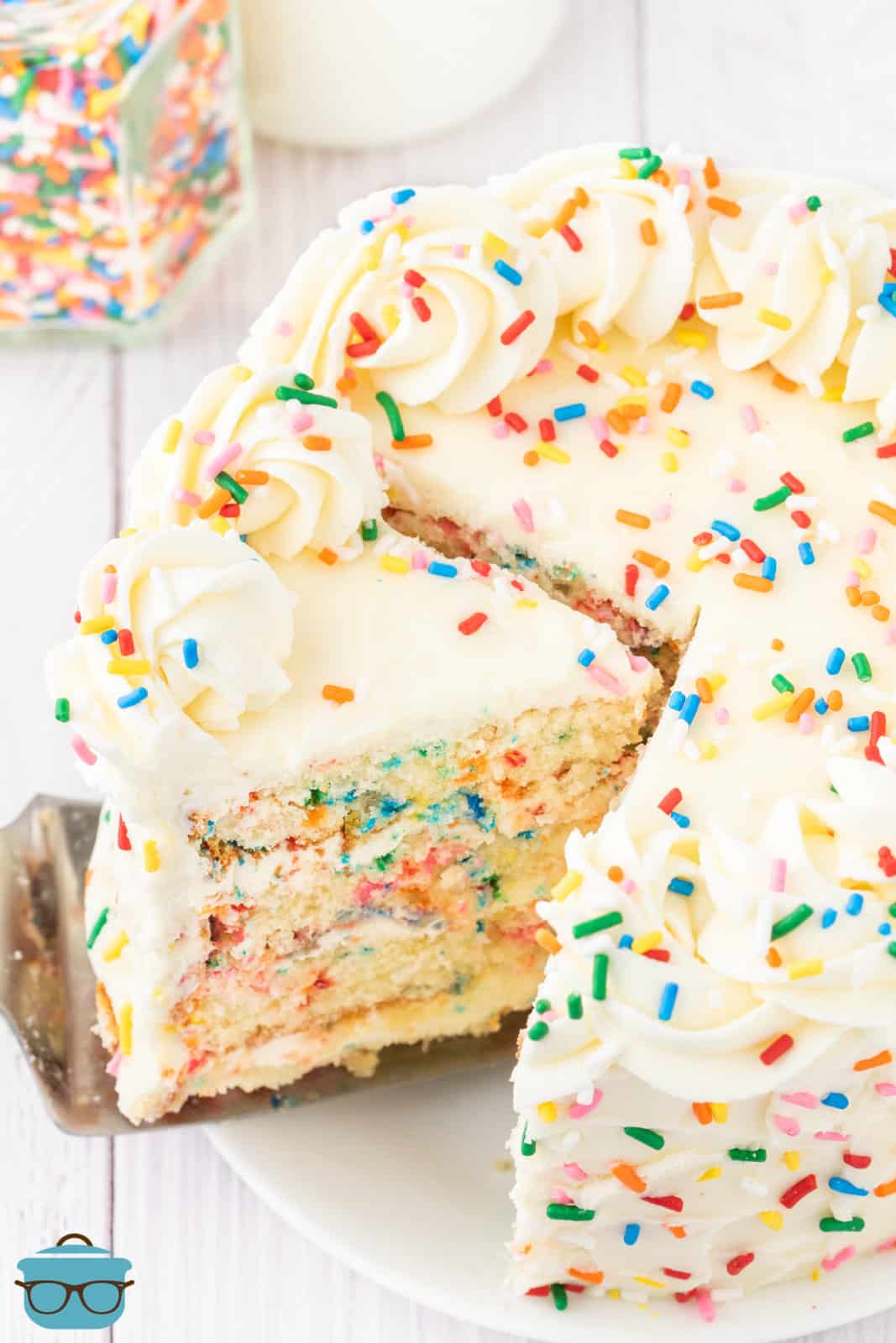 A Funfetti Cake that is layered with a slice being cut out.