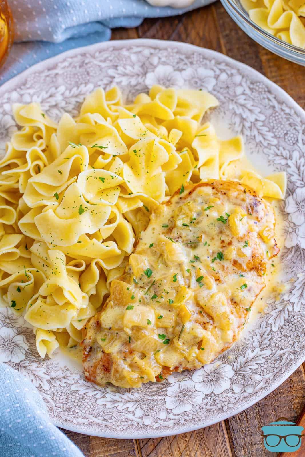 A decorative plate with creamy chicken with a side of pasta. 