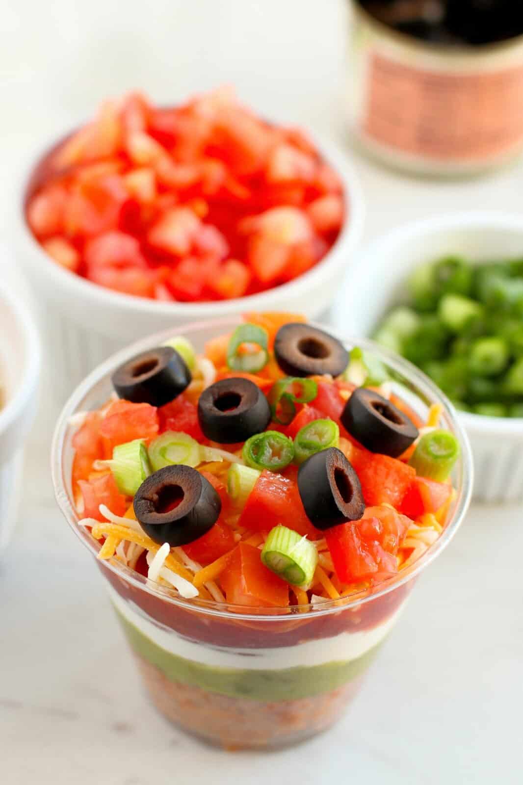 Looking down on the top few layers of the 7 layer dip in a cup.