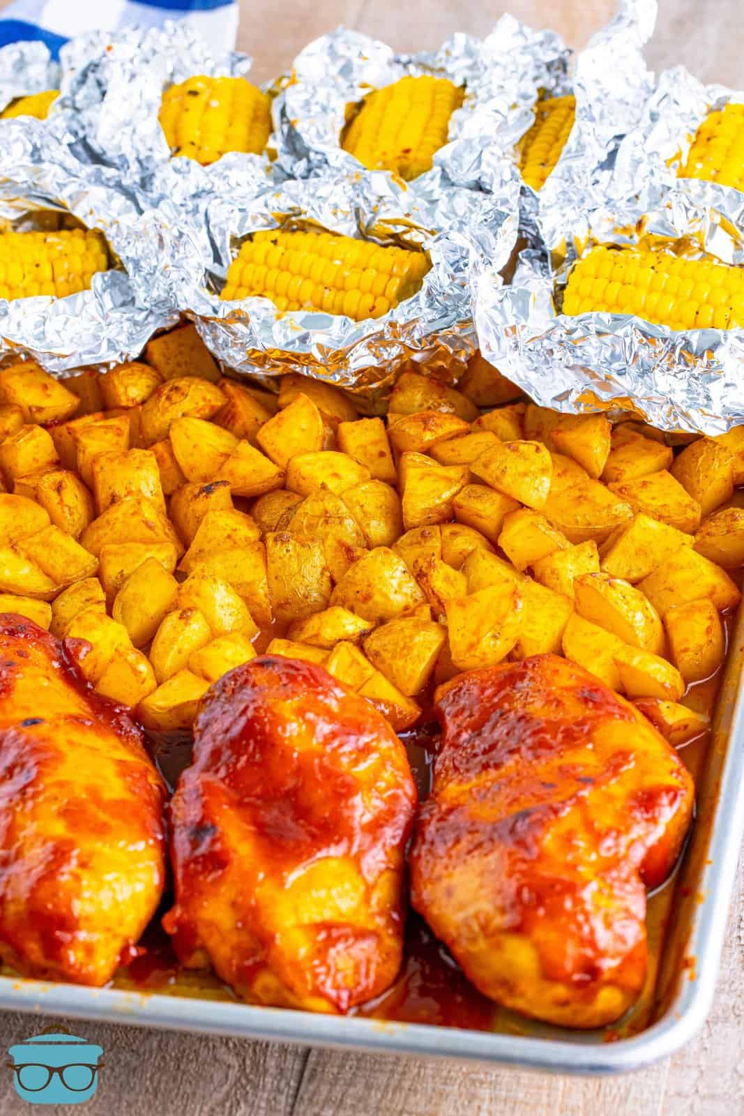 A BBQ Chicken Sheet Pan Mea with chicken, potatoes, and corn on the cob.