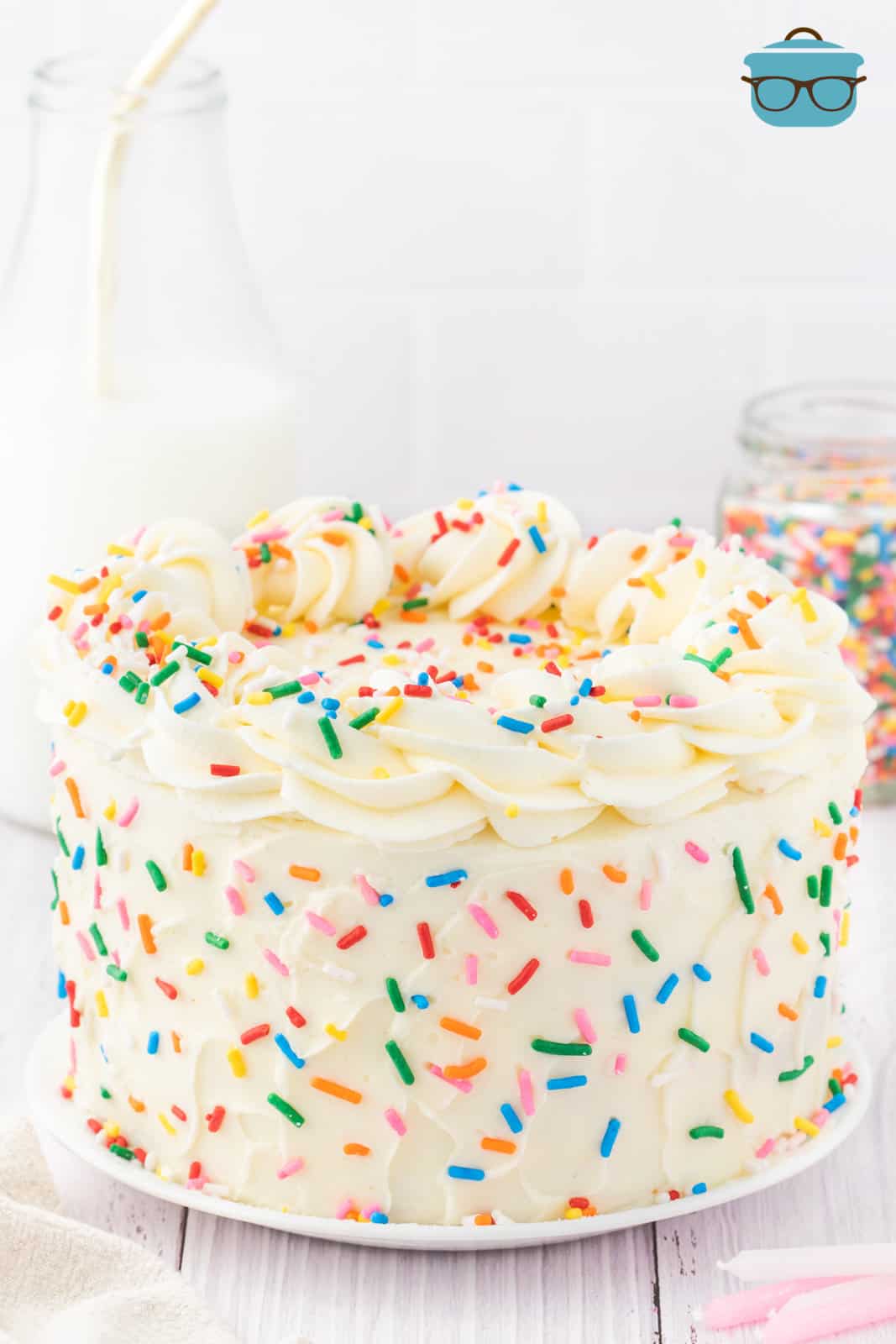 A finished Funfetti Layer Cake on a cake plate with a piped frosting edge on top.