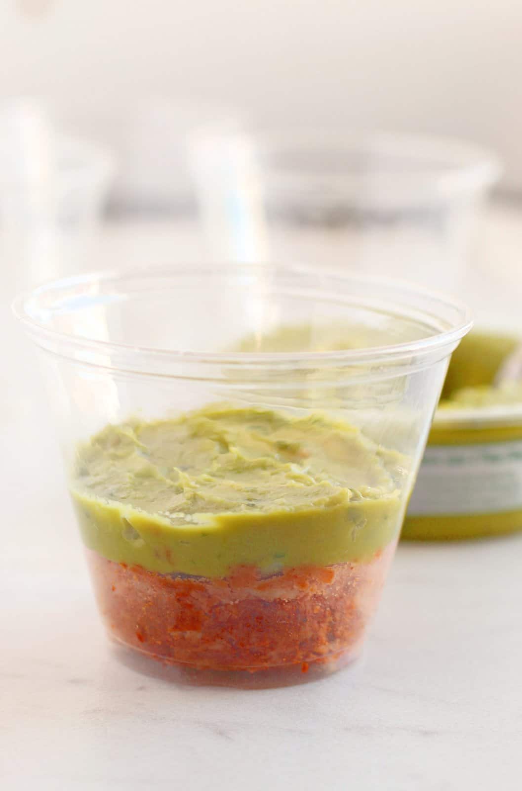 A cup with refried beans and guacamole.
