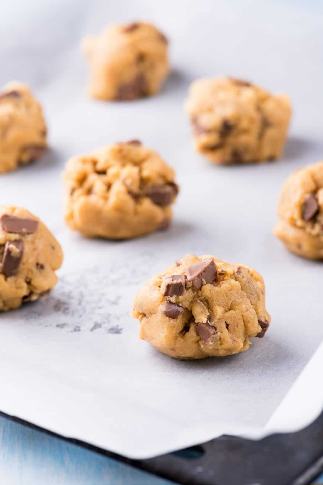 Raw cookie dough on a baking tray with parchment paper