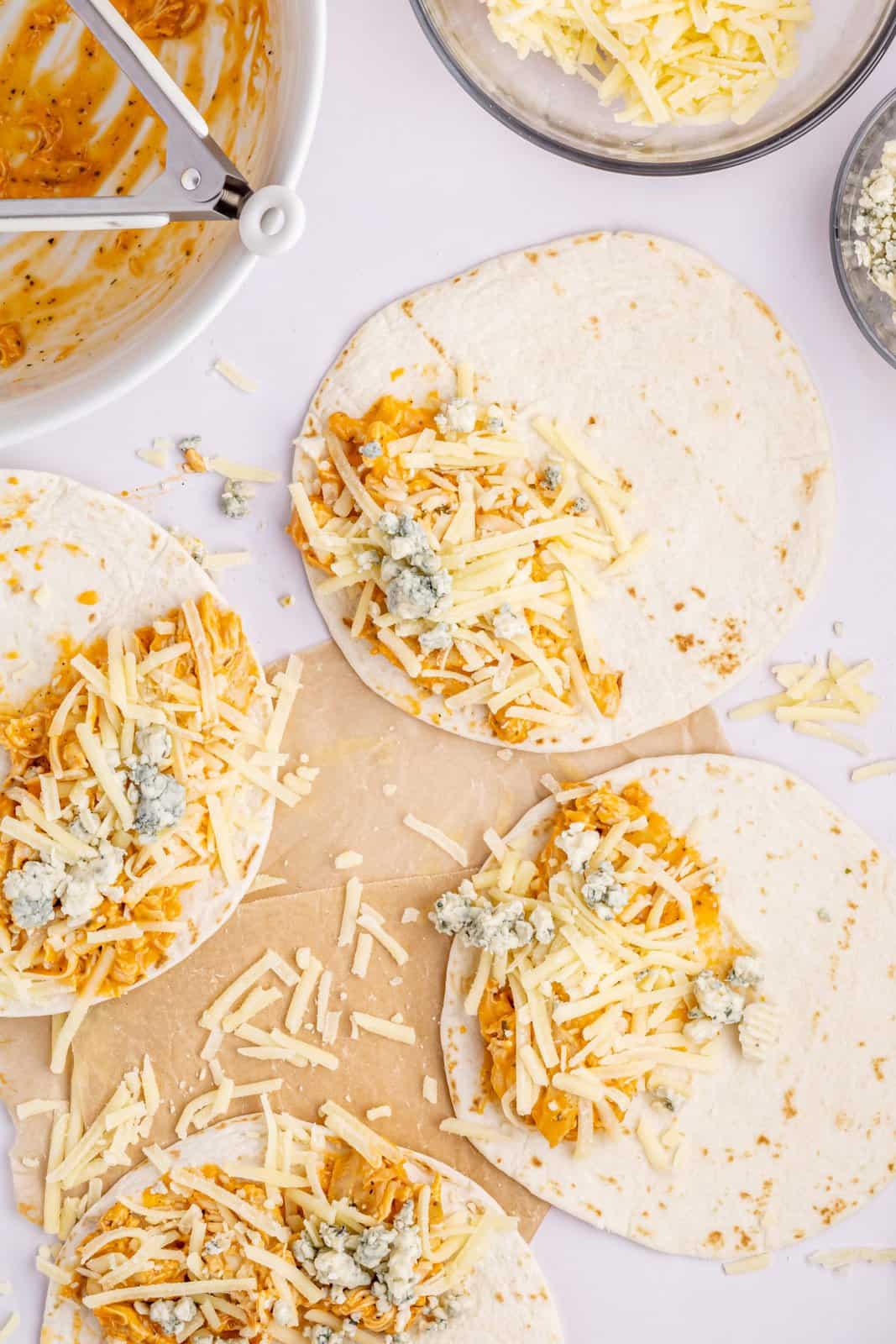 Tortillas with buffalo chicken, shredded cheese, and bleu cheese on top.