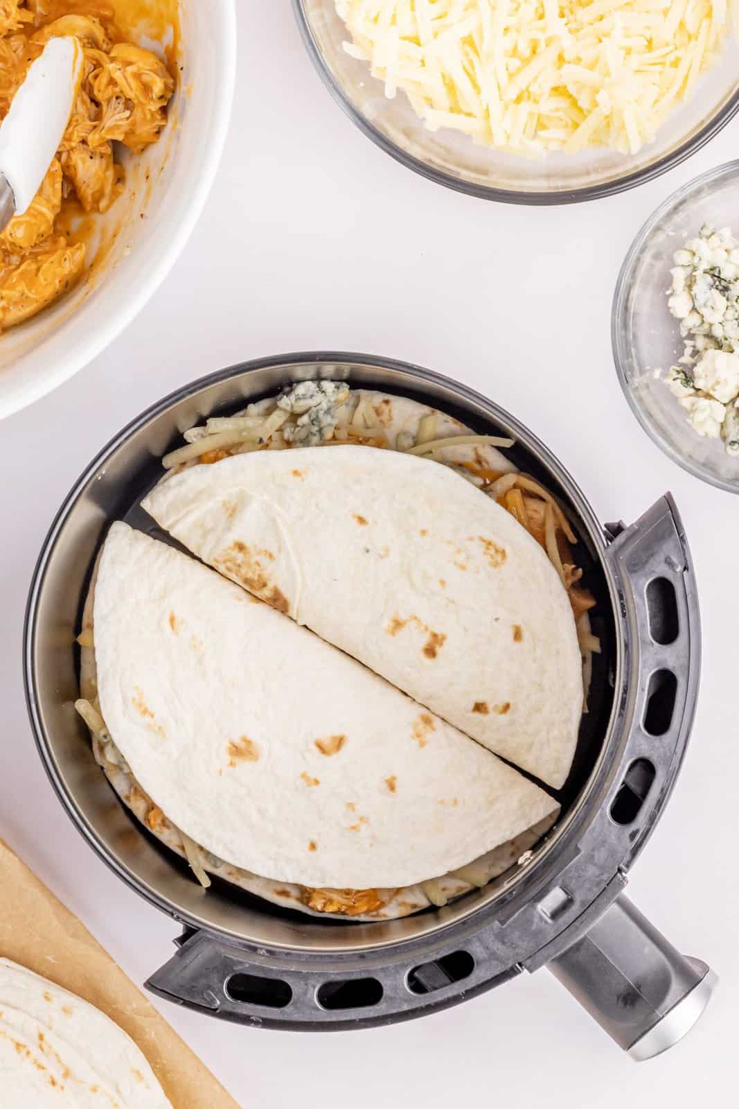 Air Fryer basket with two folded quesadillas.