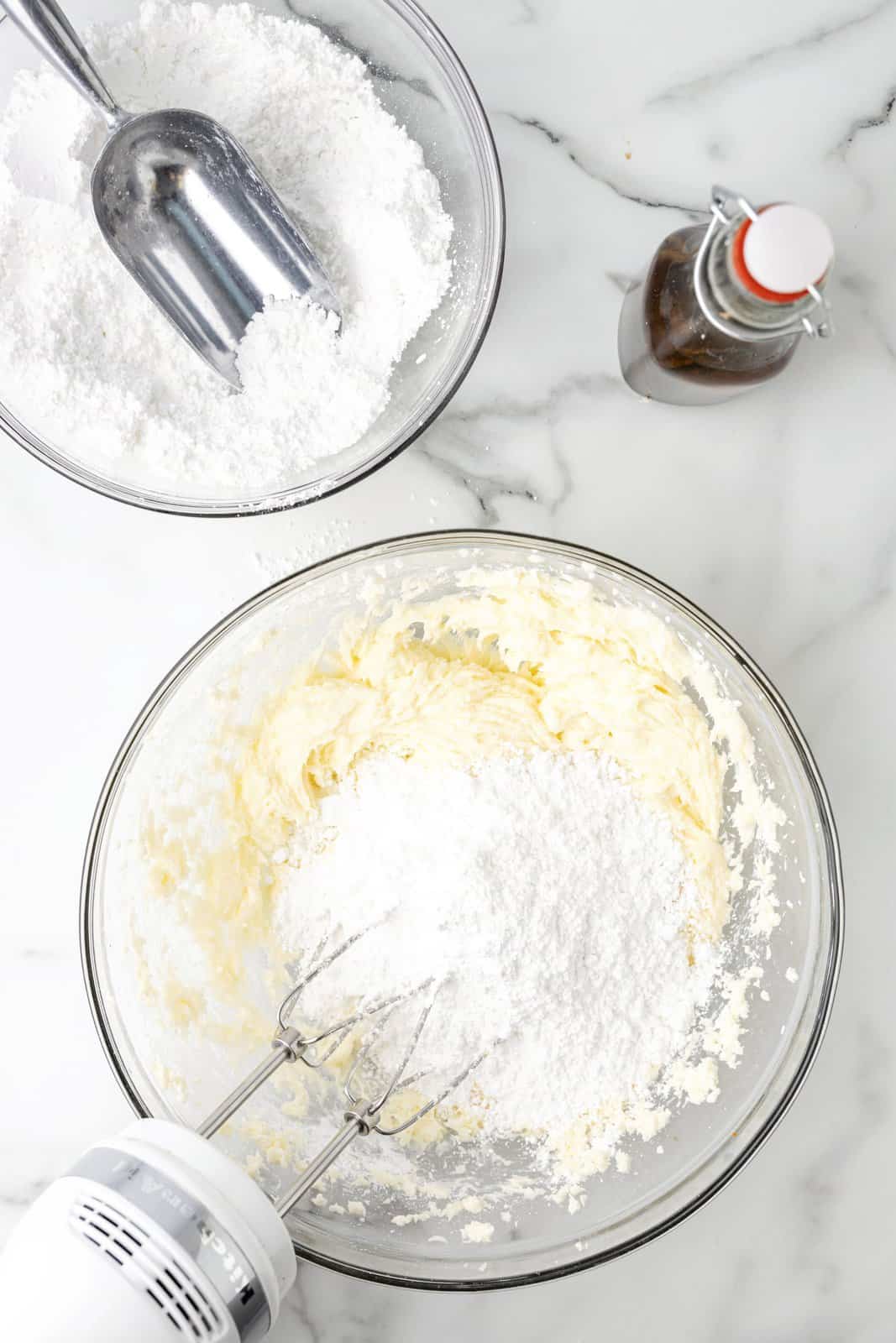 A mixing bowl with cream butter and cream cheese, vanilla extract and powdered sugar. 