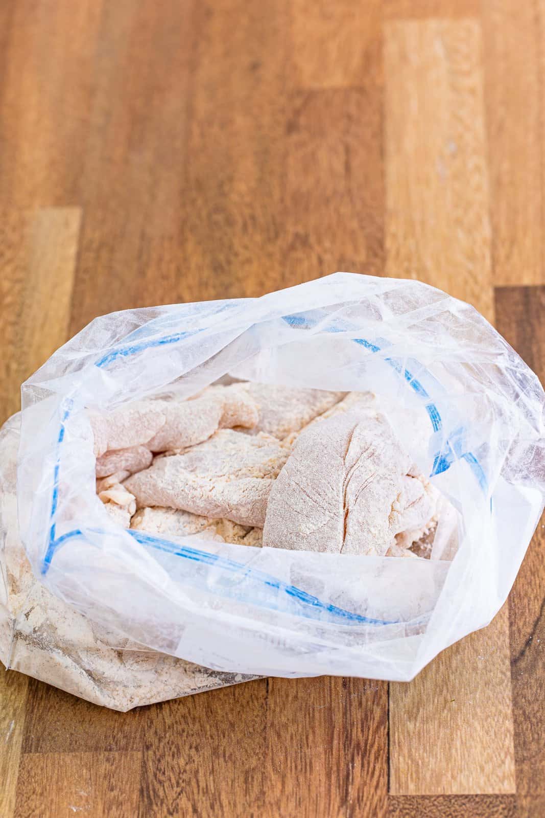 A ziplock bag with all-purpose flour, salt, pepper, paprika, garlic powder, and onion powder and chicken.