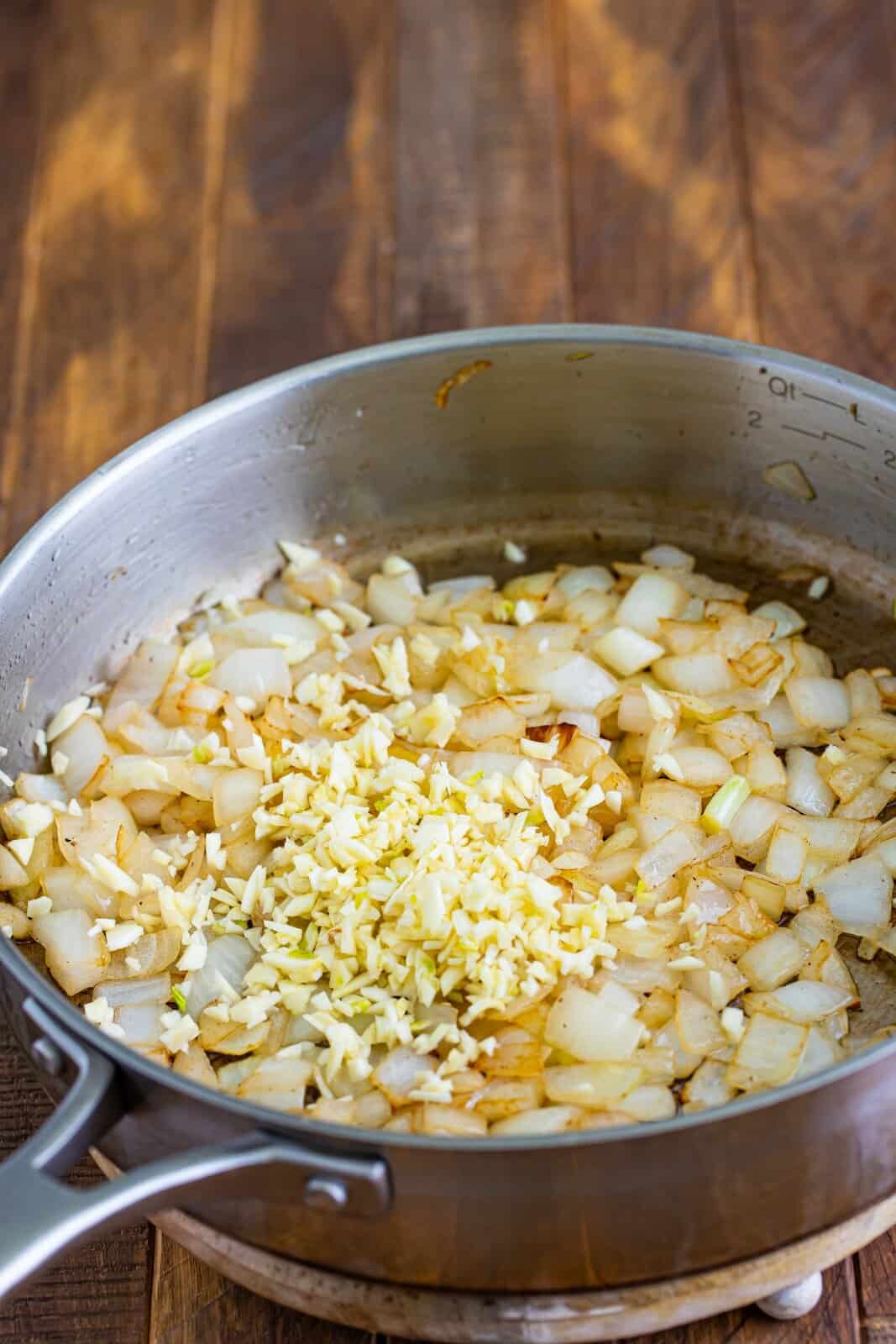 A saucepan with onion, garlic and olive oil.