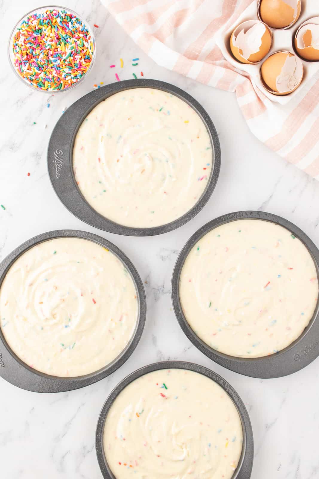Four cake pans with cake batter. 