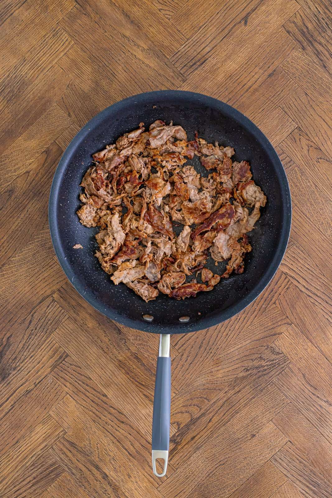 Cooked shaved steak in a skillet. 