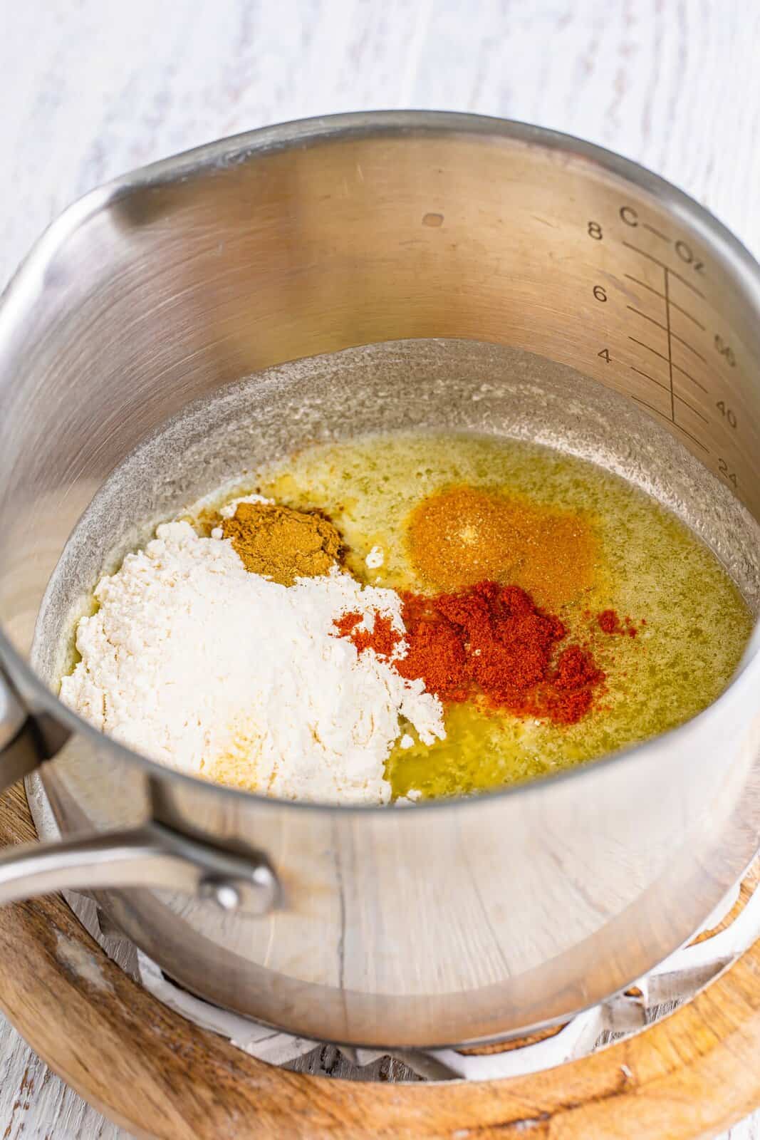 A saucepot with melted butter, flour, garlic powder, onion powder, cumin, and paprika.