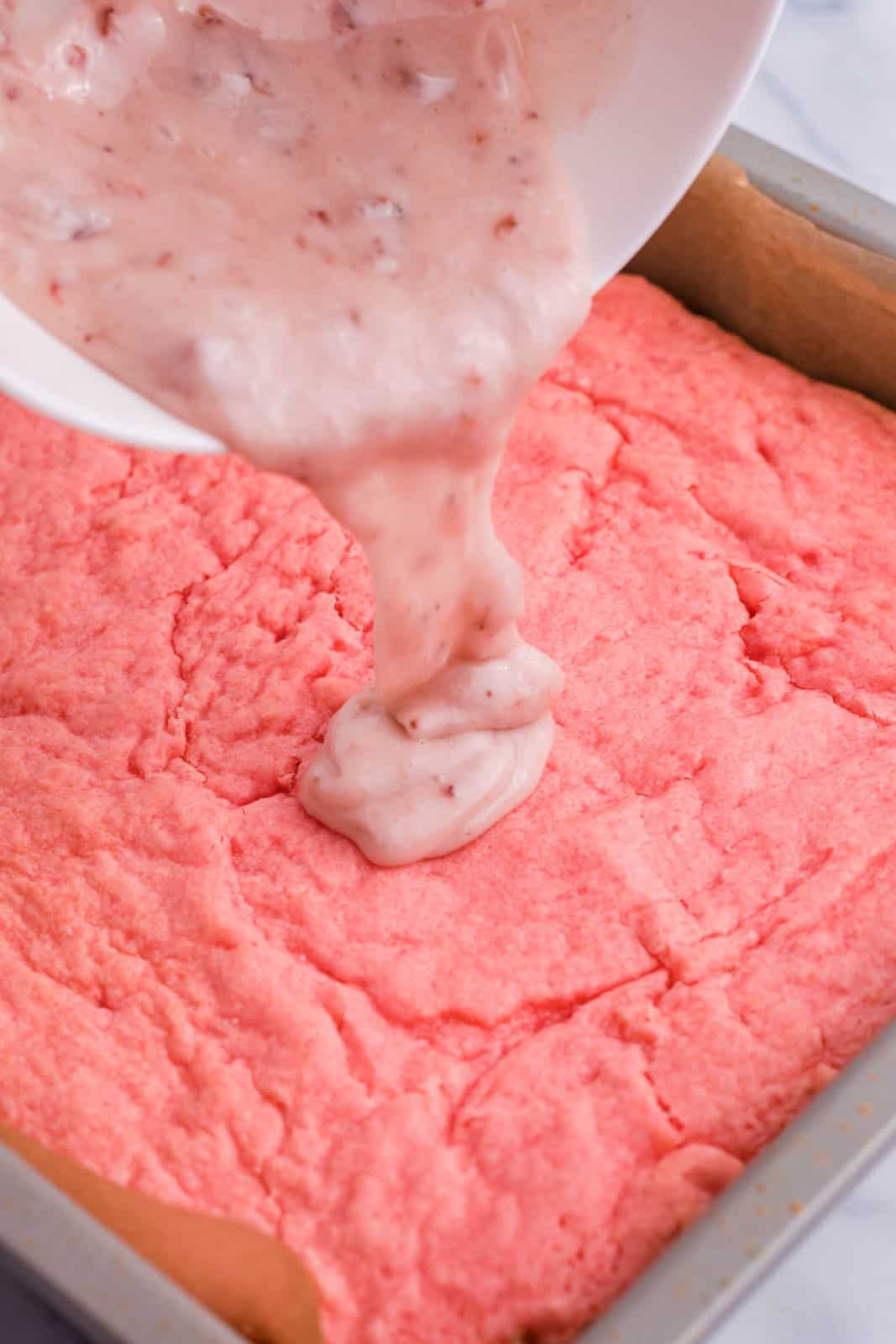 The glaze being poured on Strawberry Brownies.