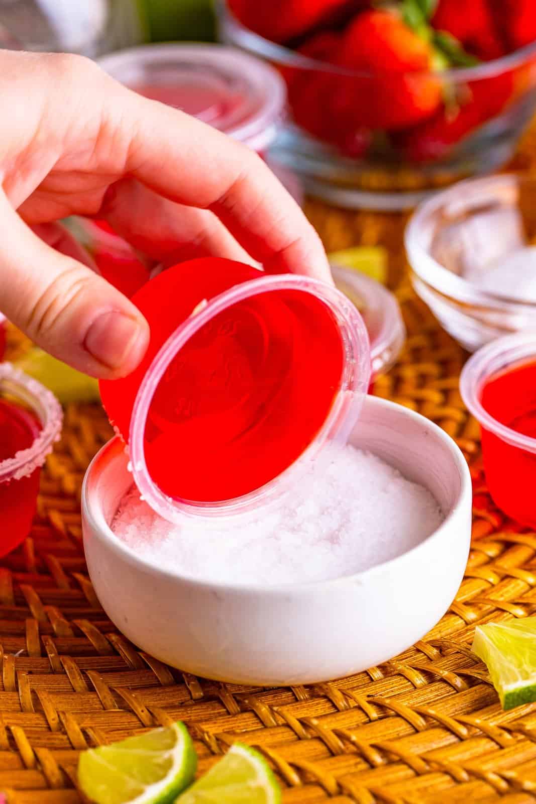 A jello shot in a cup being rolled in margarita salt. 