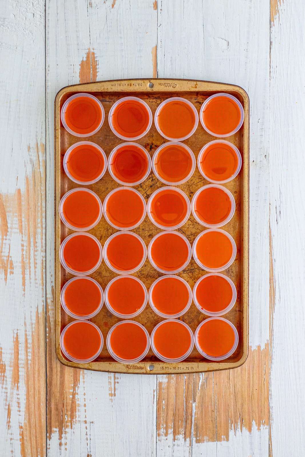Looking down on cups of layered orange and cherry jello shots in cups.