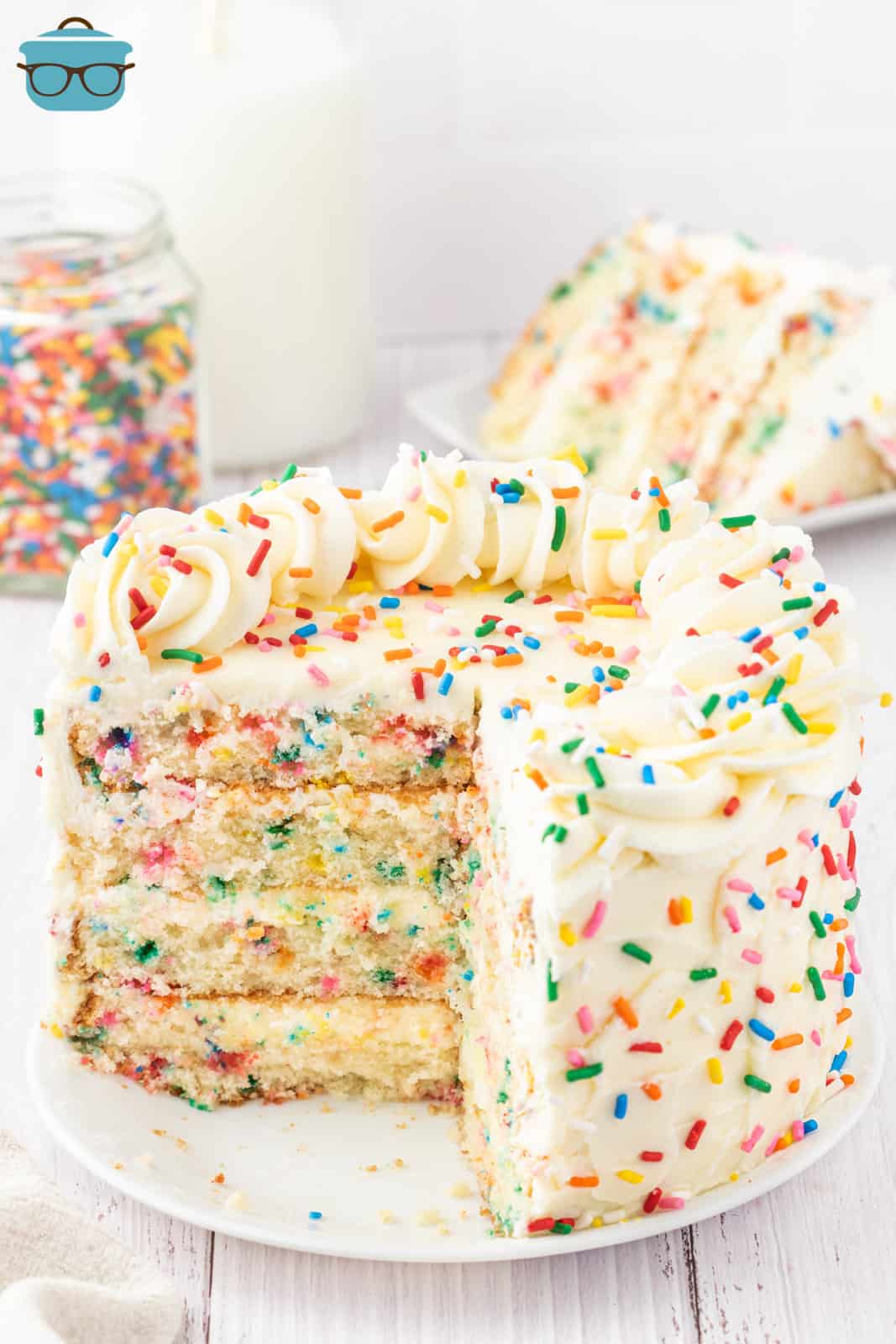 A layered homemade Funfetti cake from scratch with a piece removed. 