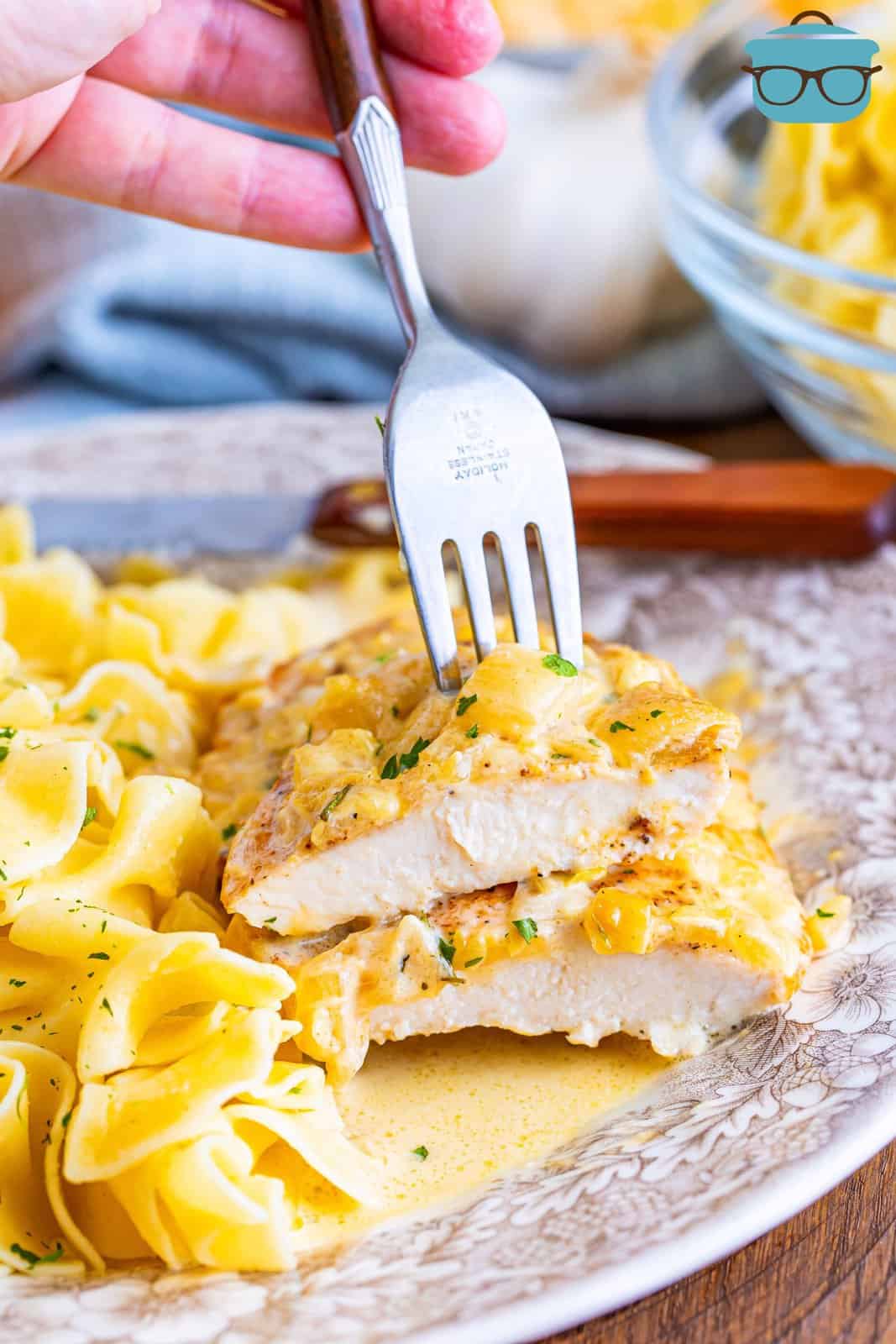 A fork holding a sliced piece of Creamy Garlic Chicken with pasta.