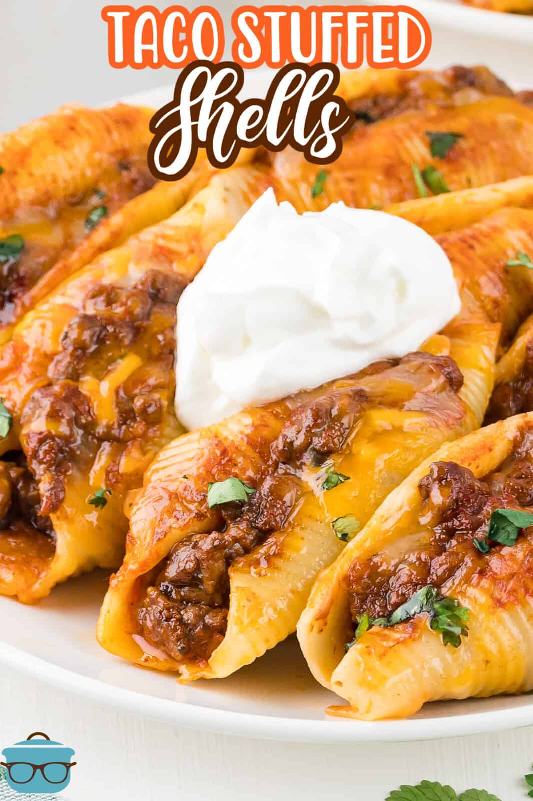 A dollop of sour cream sitting on top of some taco stuffed shells on a plate.