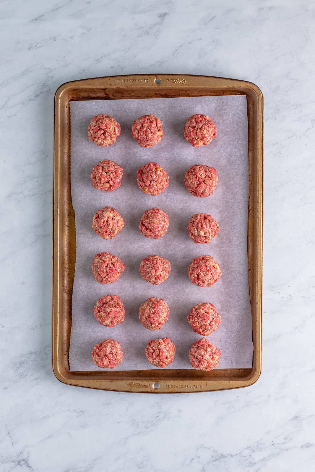 Meatballs on a parchment lined baking tray.