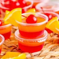 Two Tequila Sunrise Jell-O Shots with a garnish on the top one.