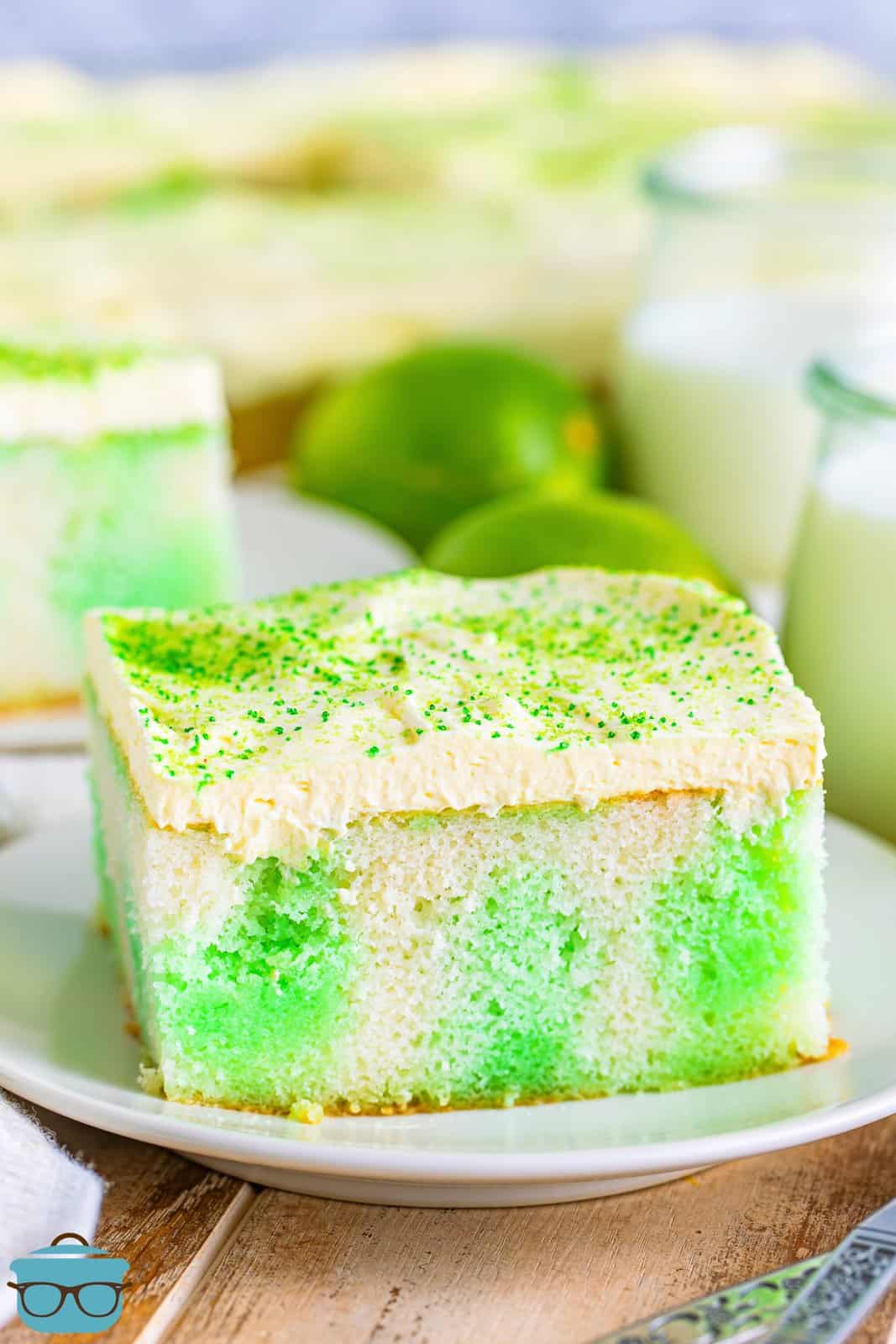 A rectangular piece of lime Jell-o poke cake with sprinkles on top.