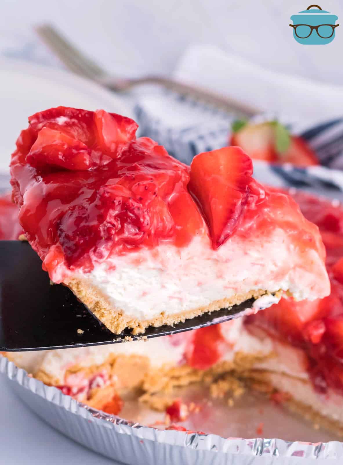 A pie serving utensil with a slice of Strawberry Cream Cheese Pie.