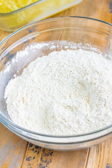 A mixing bowl with flour, sugar, baking powder, salt, garlic powder, and onion powder.