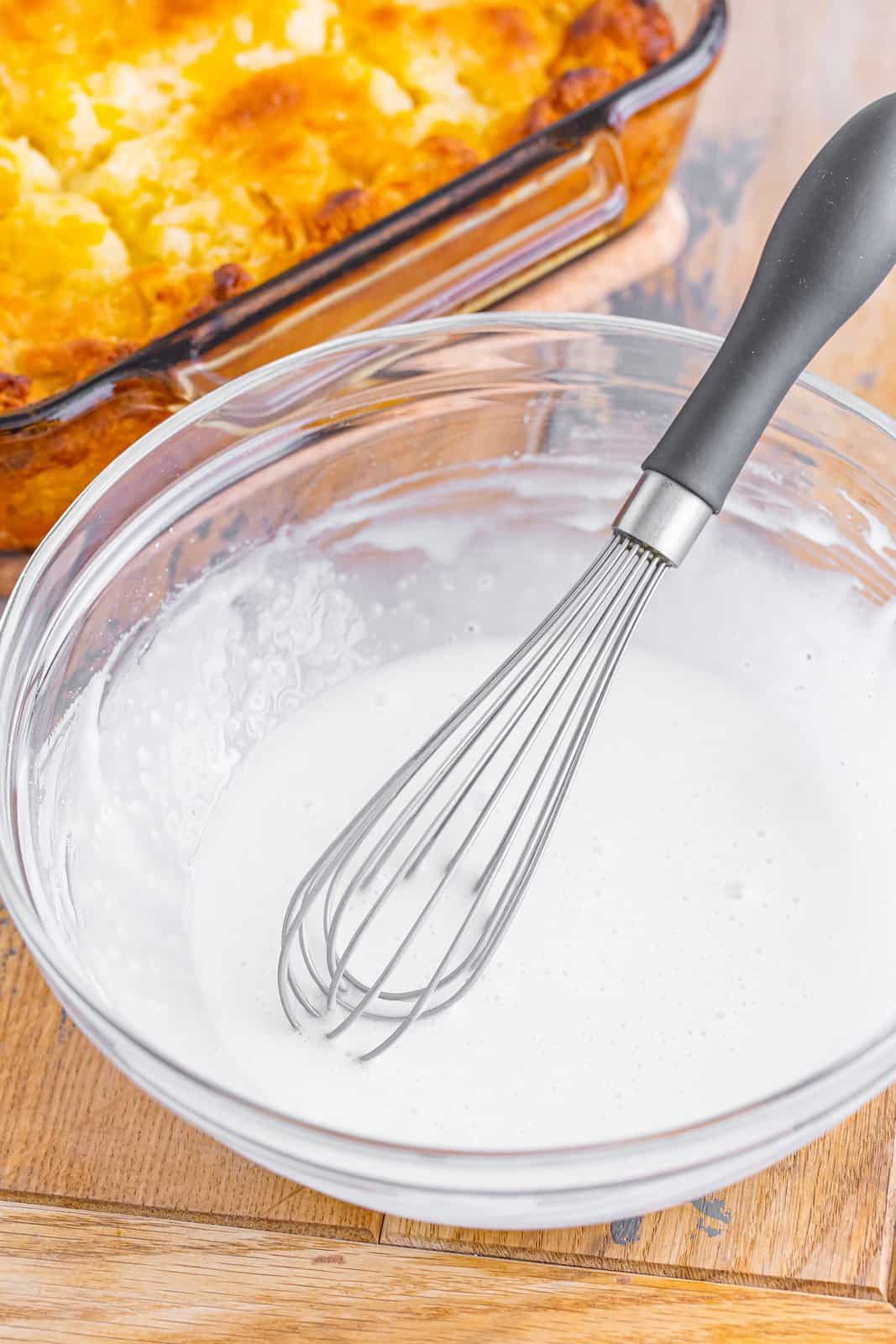 Powdered sugar and milk in a mixing bowl with whisk.