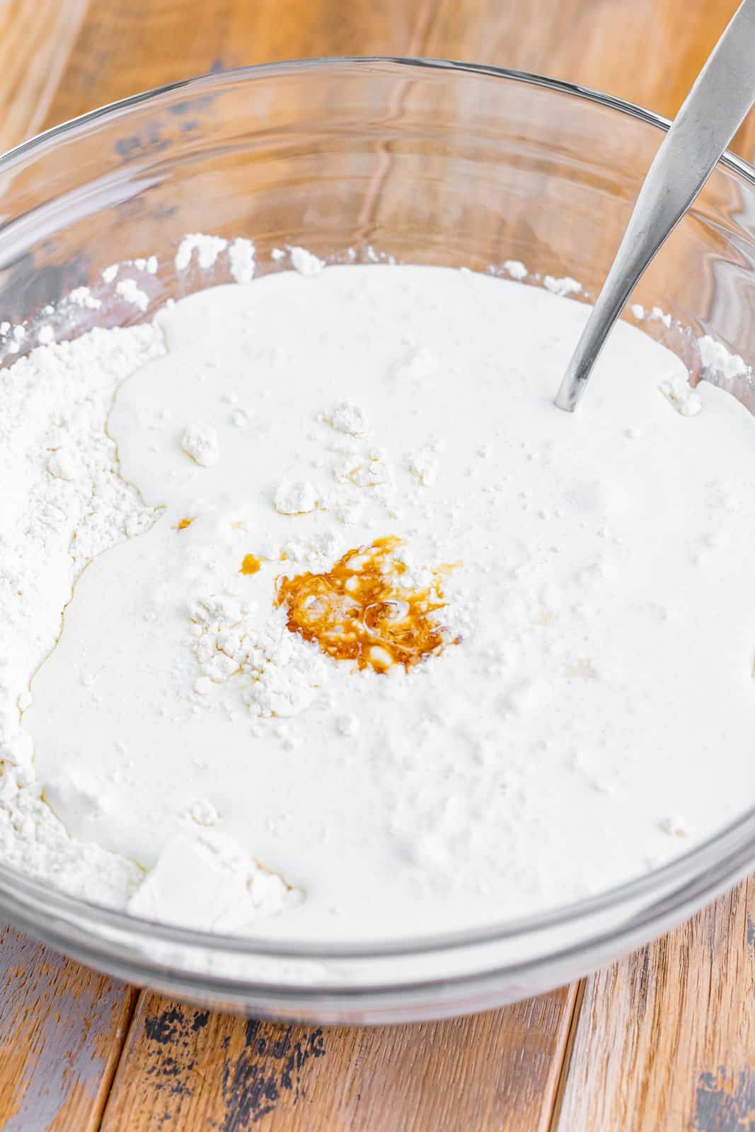 A mixing bowl with flour, sugar , heavy cream, vanilla, and baking powder.