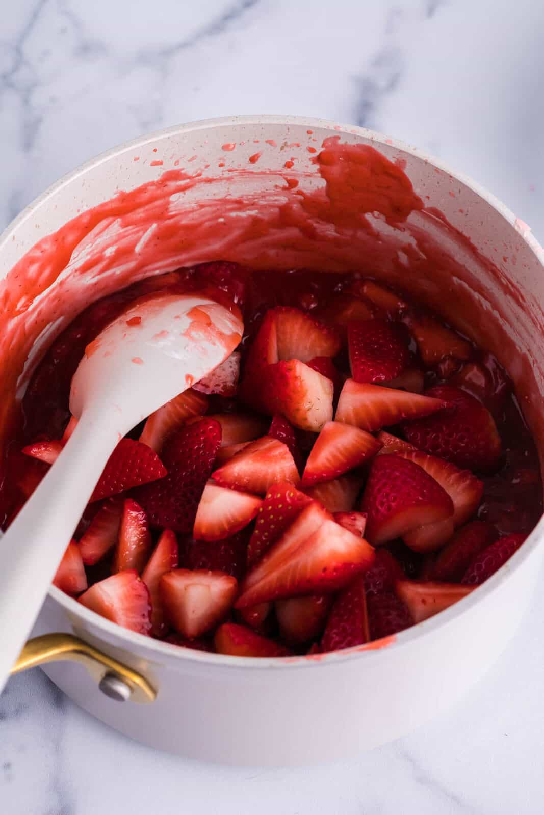 A sauce pan with strawberries and sauce. 