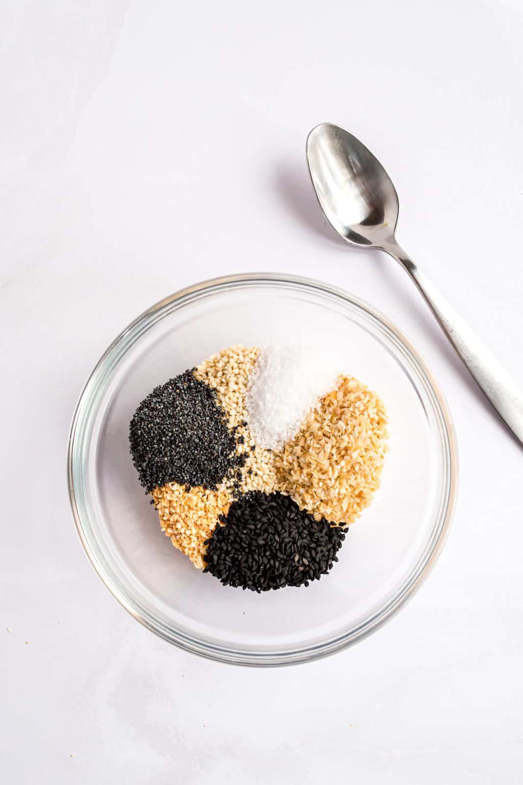 Poppy seeds, white sesame seeds, black sesame seeds, dried minced onion, dried minced garlic, and salt in a mixing bowl.