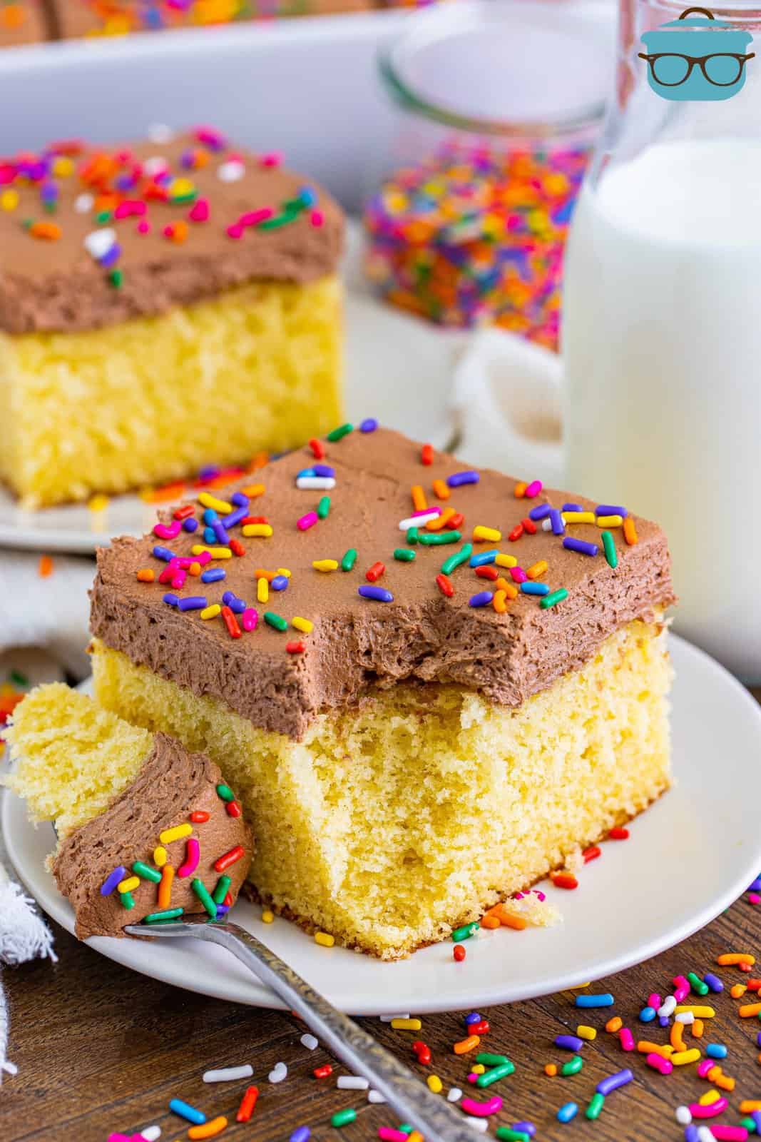 A plate with a slice of yellow cake with chocolate frosting and a bite taken out.