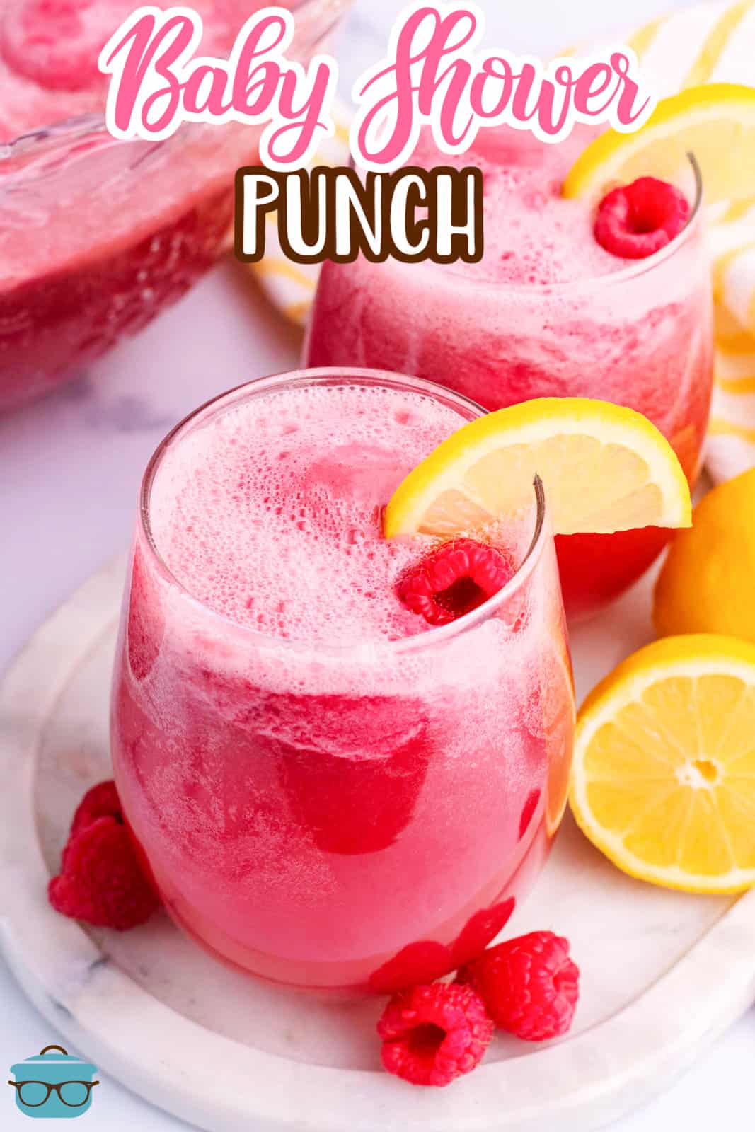 A glass of bright pink Baby Shower Punch with a lemon wedge.