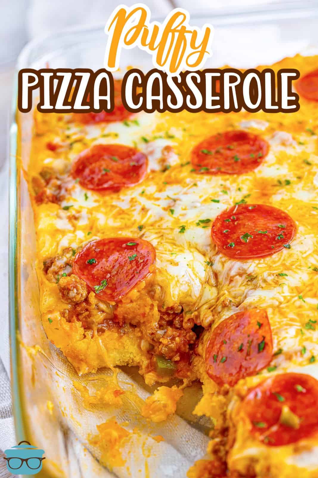 A baking dish with some Puffy Pizza Casserole with a serving taken out.