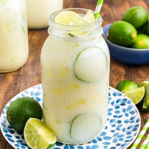 A glass jar of limeade sitting on a plate.