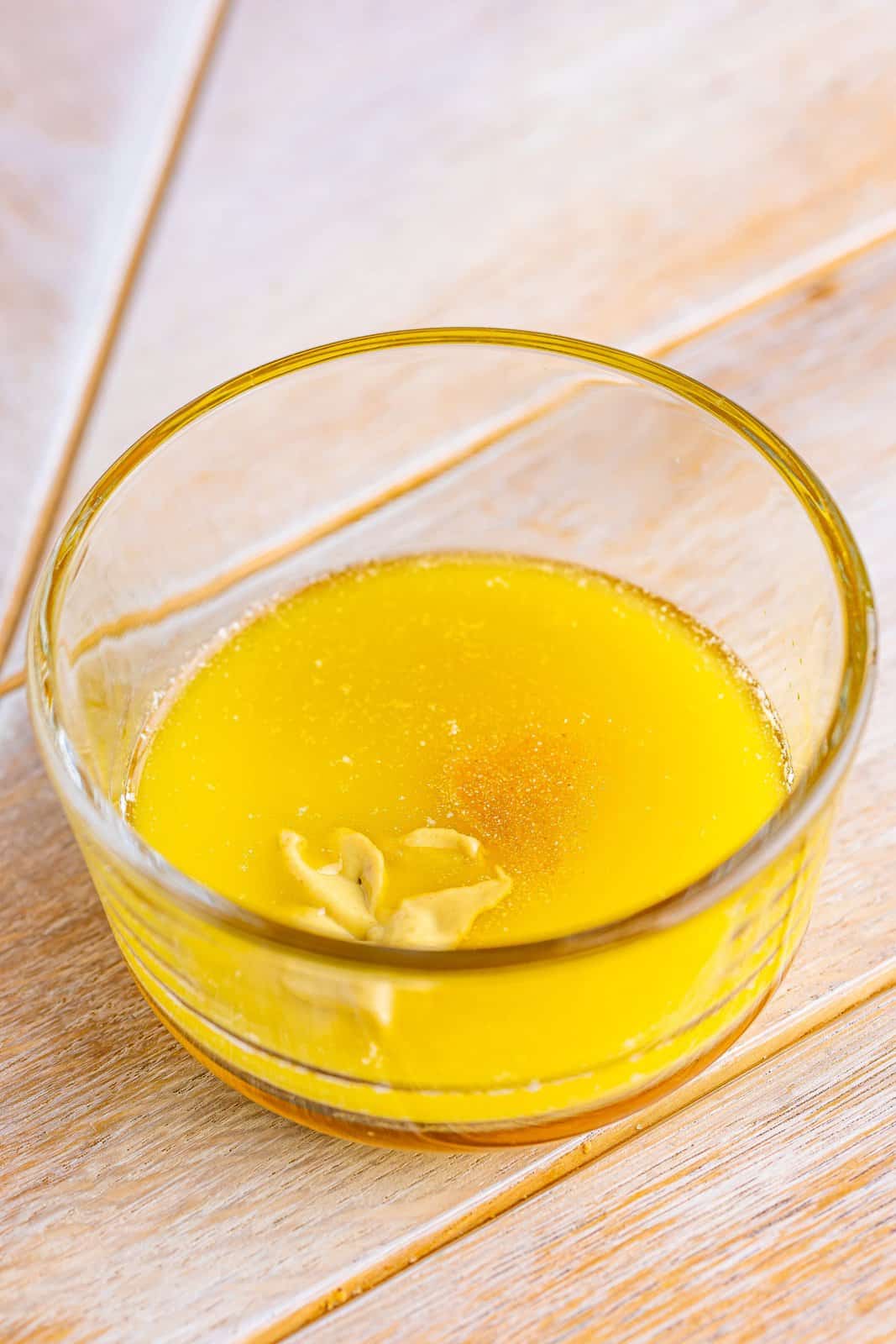 Melted butter, honey, dijon mustard and garlic powder in a small glass bowl.