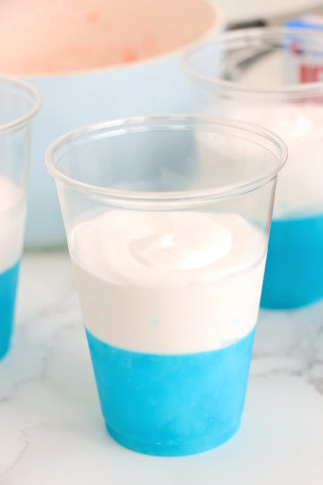 Berry Blue Jello layer and a whipped cream layer on top in a cup.
