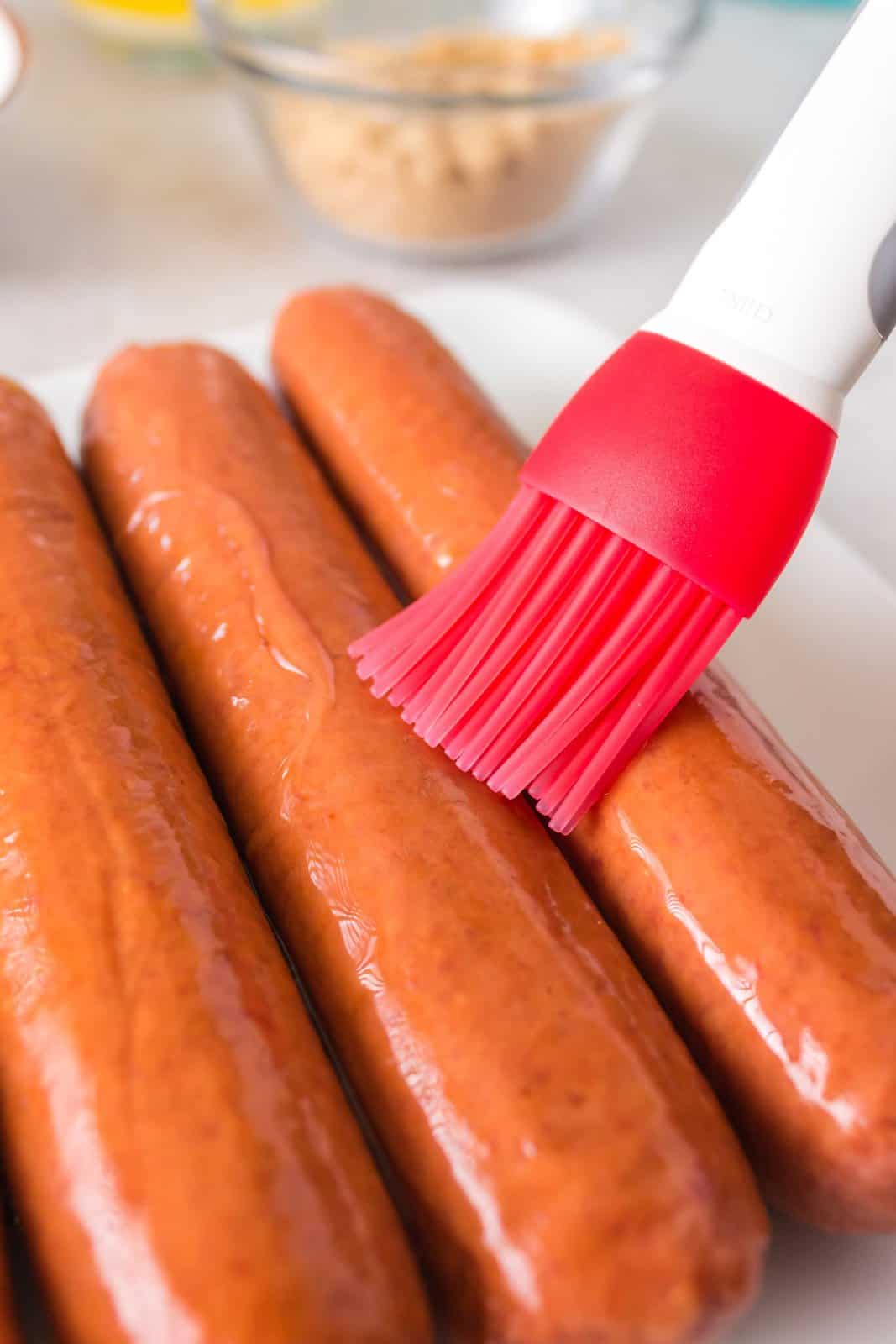 Hot dogs being brushed with oil.
