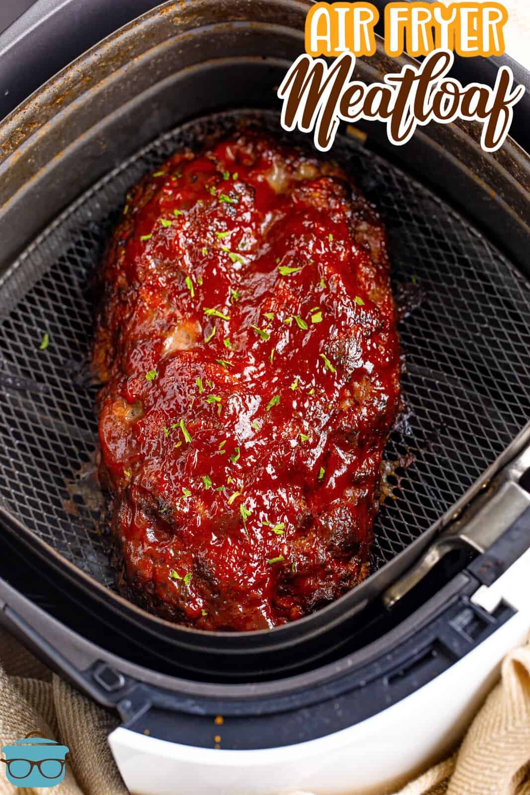 An air fryer basket with a loaf of meatloaf.