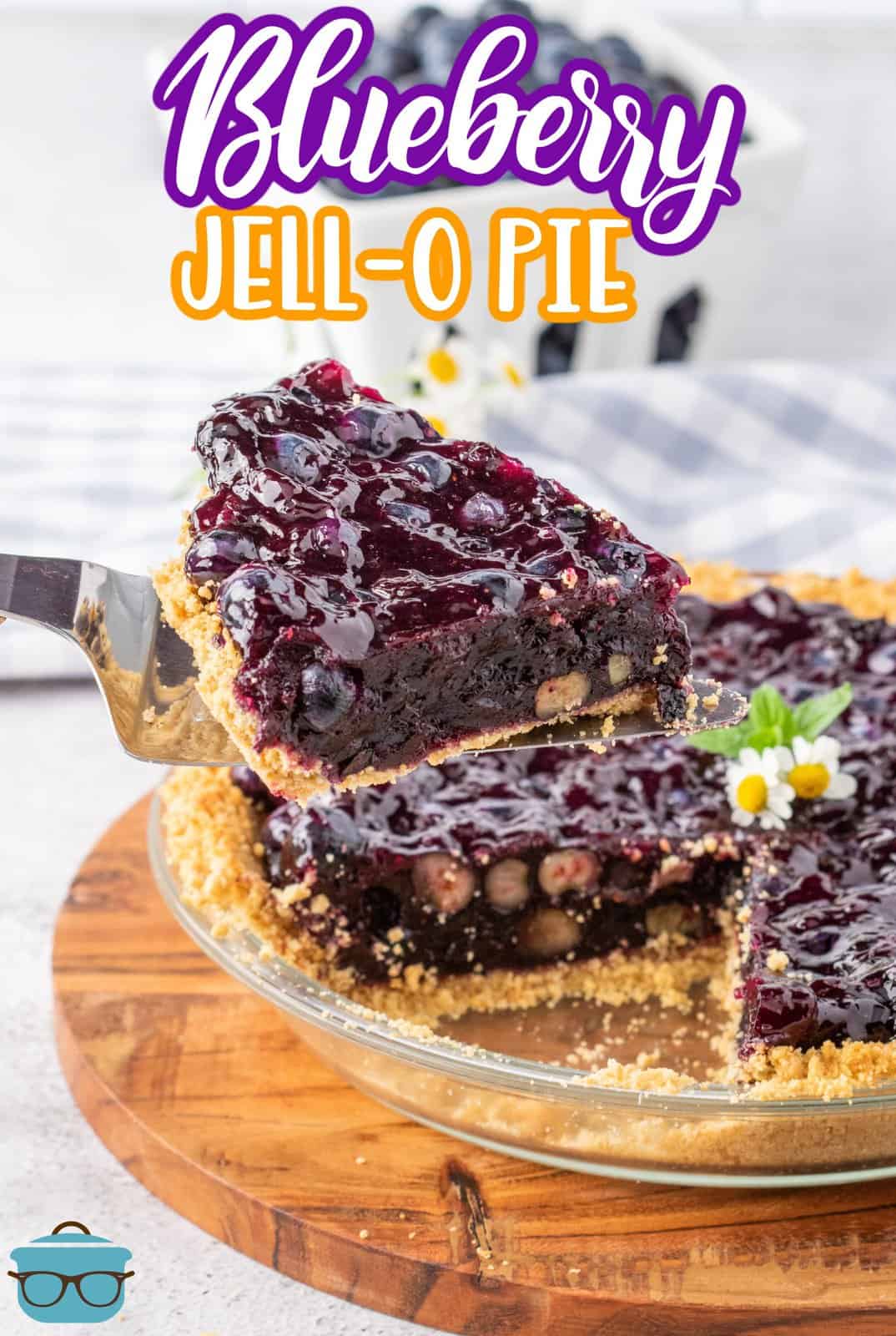 A pie serving utensil holding a slice of Blueberry Jell-O Pie above a plate with the rest of the homemade pie.