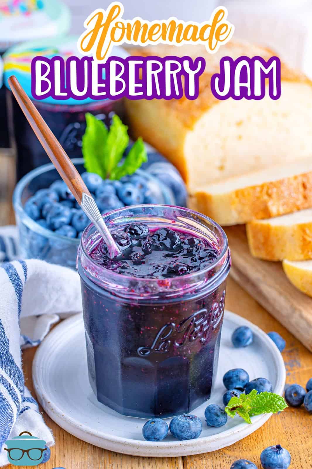 A jar of homemade blueberry jam with a spoon in it.