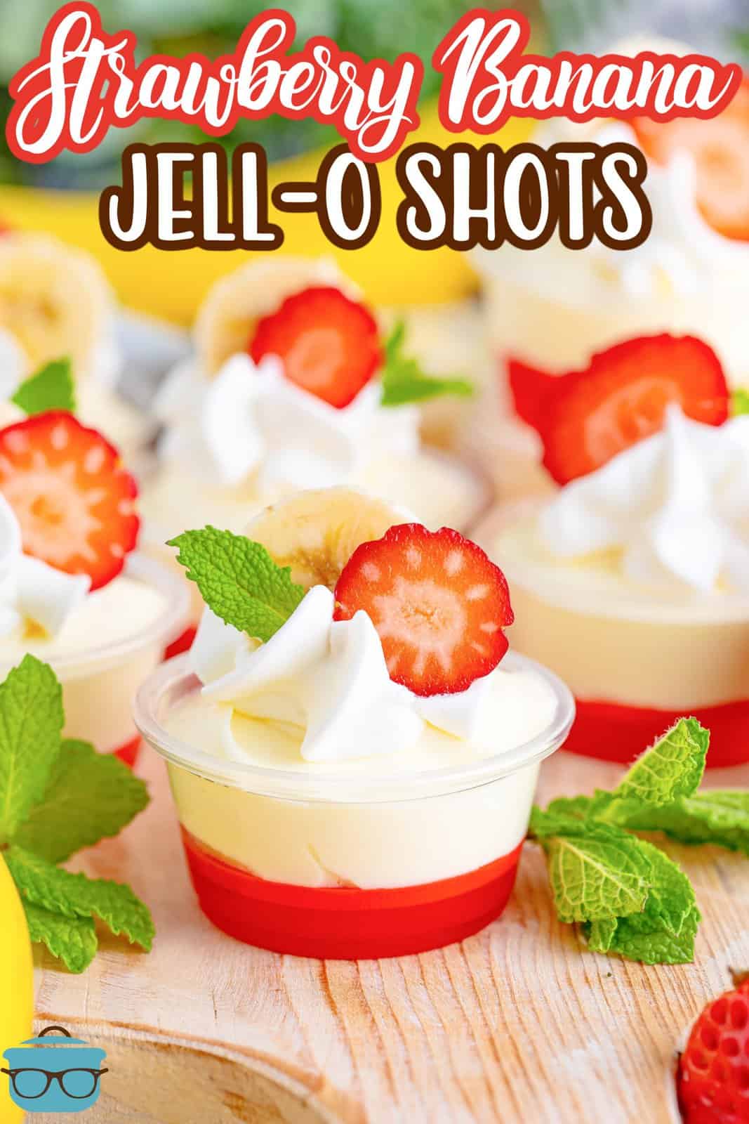A few Strawberry Banana Jello Shots with whipped cream and strawberry slices on top.