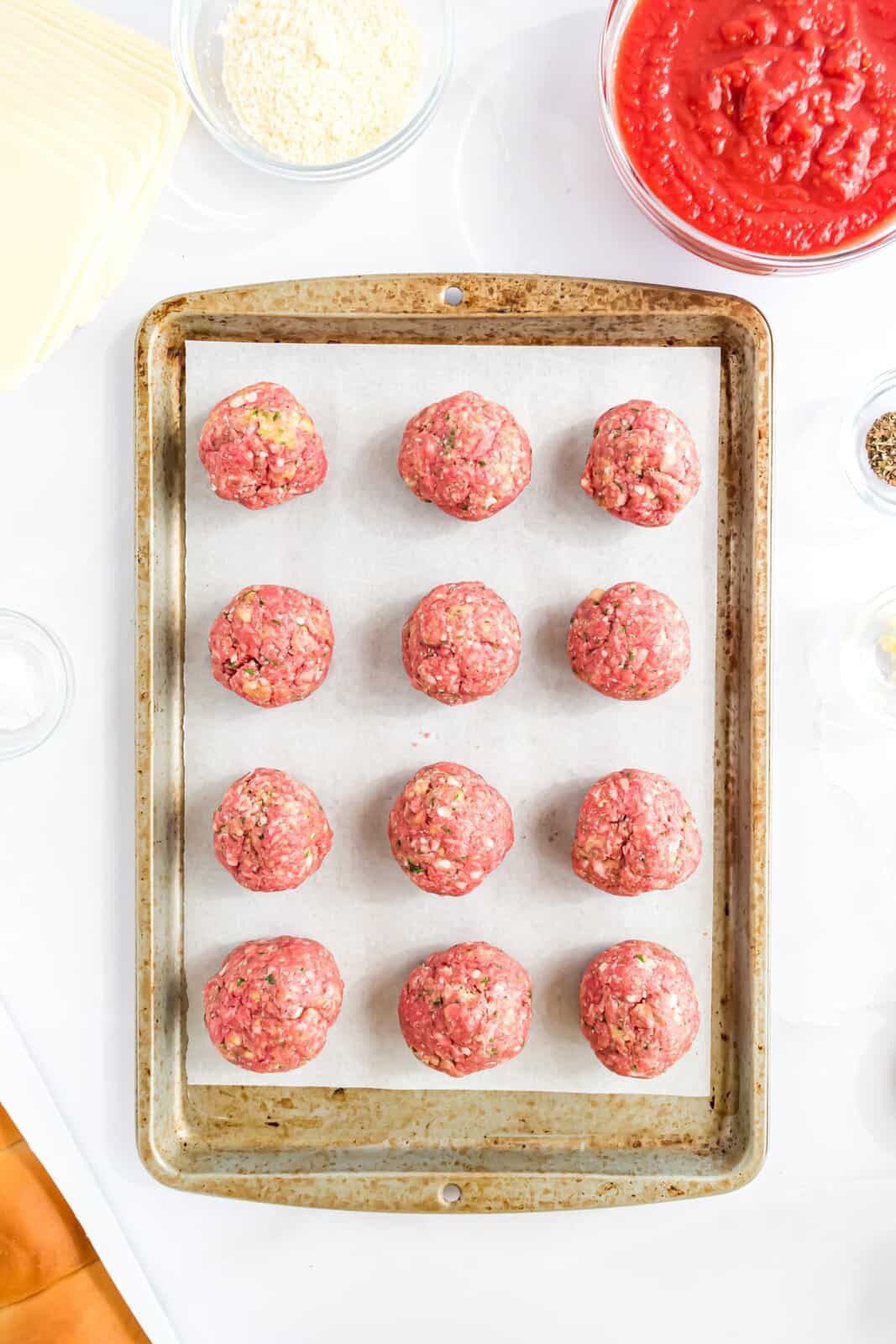 Meatballs on a parchment lined baking sheet.